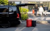 Black minivan with rear hatch open and luggage on the pavement